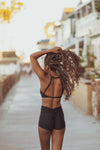 Model wearing Aura7 Activewear Del Mar sports bra while walking on a public street near the beach