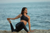 Model wearing Aura7 Activewear one shoulder Hermosa sports bra while doing yoga on the beach