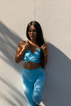 model wearing Aura 7 Activewear Fresh Air Malibu Top posing in the shade against a wall outdoors