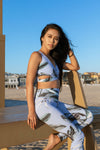 Model wearing Aura 7 Activewear Tropic Vita Legging Yoga Pants sitting on a lifeguard tower at the beach