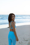 Model wearing Aura 7 Activewear Fresh Air Del Mar Top walking on the beach during sunset