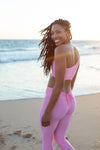 Model wearing Aura 7 Activewear Flower Hermosa Top walking on the beach and turning back to look at the camera